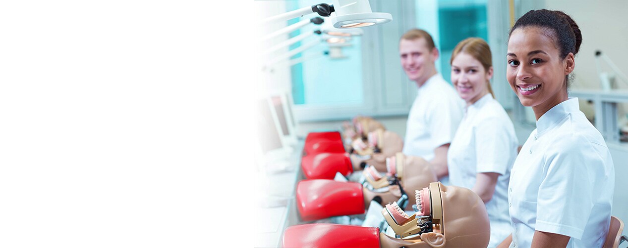 A dental professional wearing safety PPE gear and white lab coat smiling compassionately